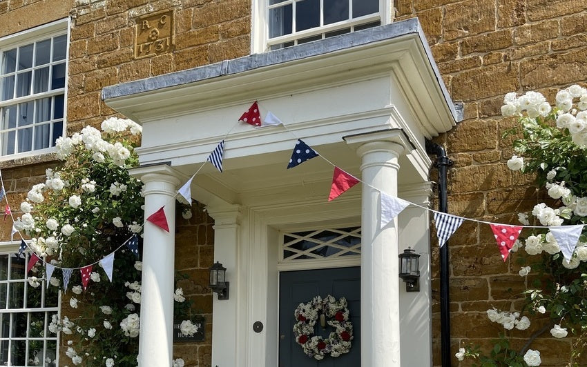 Trooping of the colour bunting with Iceberg climbing rose, David Austin Roses