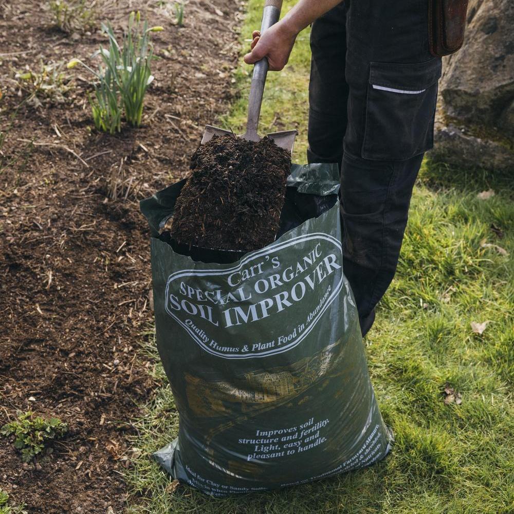 Man using a spade to spread compost on the ground
